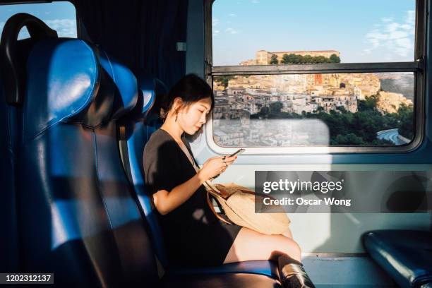 young woman using smart phone in train - vacation train stock pictures, royalty-free photos & images