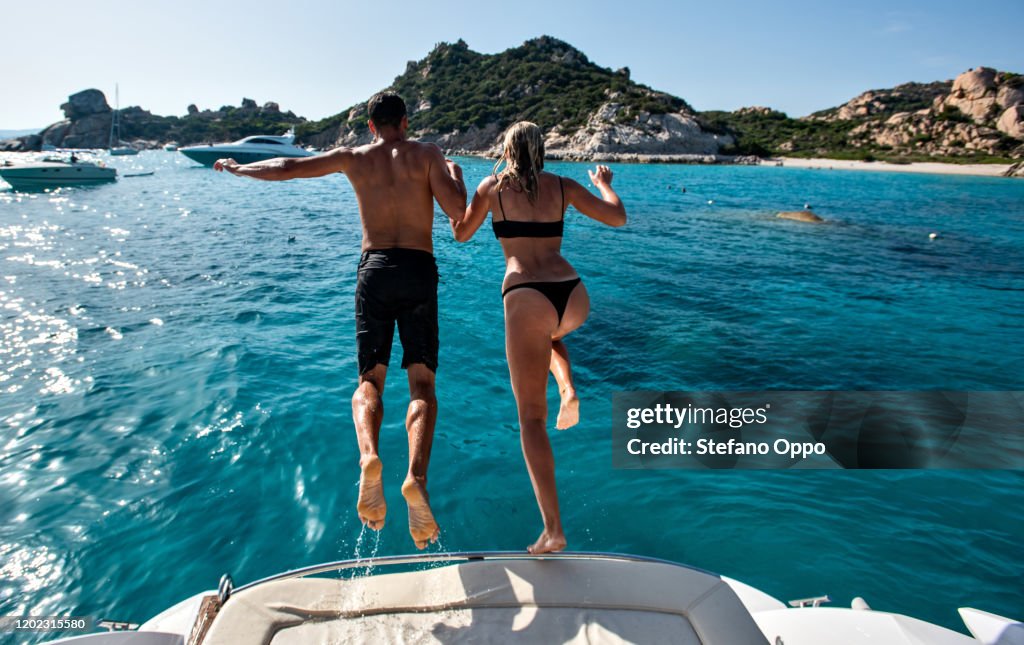Young couple jumping into sea from yacht, La Maddalena island, Sardegna, Italy