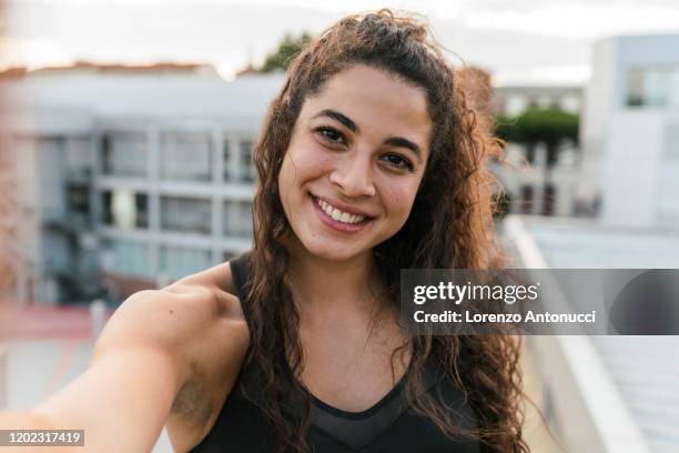 young woman taking selfie on rooftop deck - woman selfie stockfoto's en -beelden