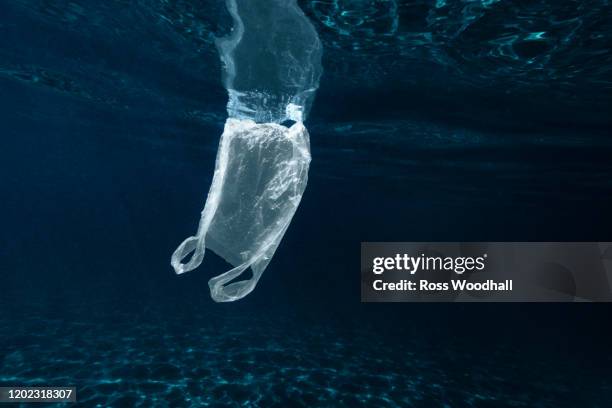 plastic bag floating in sea - sea pollution stock pictures, royalty-free photos & images