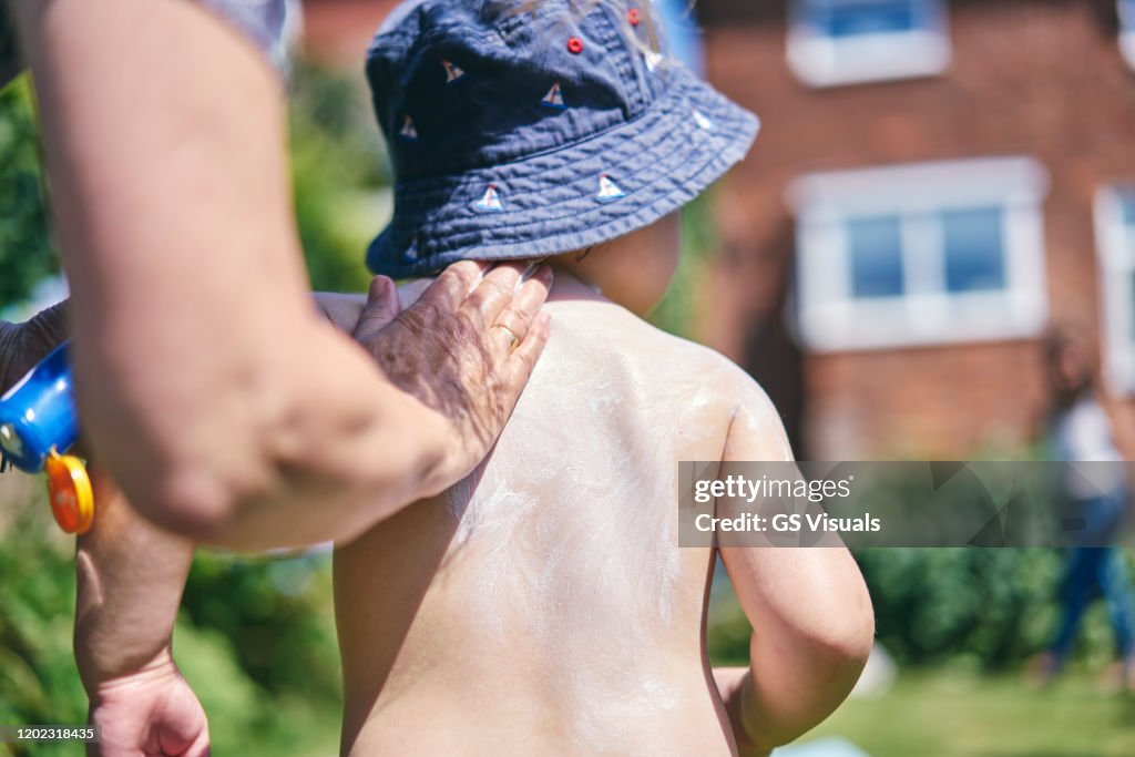 Grandmother putting sun lotion on grandson