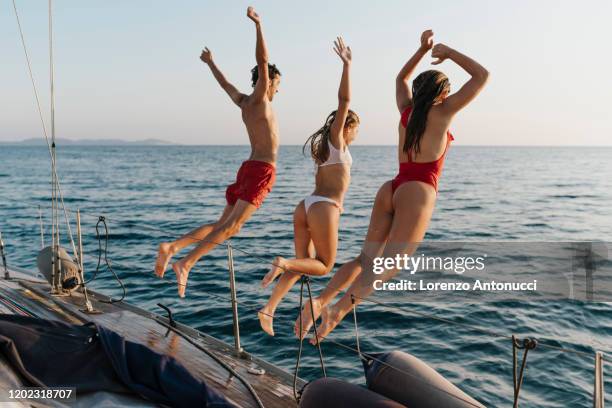 friends jumping off sailboat into sea, italy - jumping of boat photos et images de collection