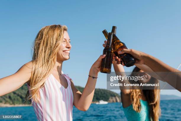 friends toasting with beer on sailboat, italy - italy beer stock-fotos und bilder