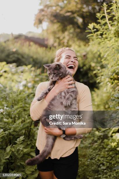 woman gardener carrying cat in garden - holding cat imagens e fotografias de stock