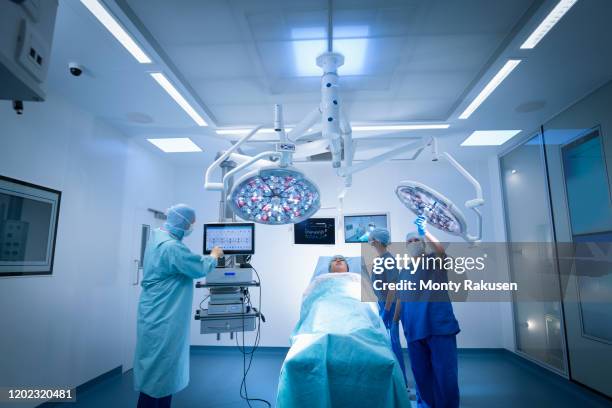 nurses, surgeon and patient in operating theatre in hospital setting - man lying on operating table stock pictures, royalty-free photos & images
