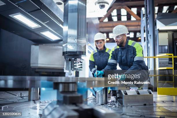 male and female specialist lathe operators in steelworks - metal factory stockfoto's en -beelden