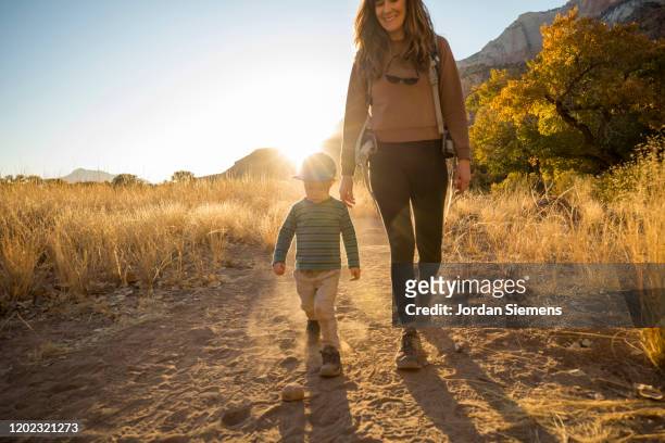 a mother and her son hiking a scenic trail at sunset - mid adult stock-fotos und bilder