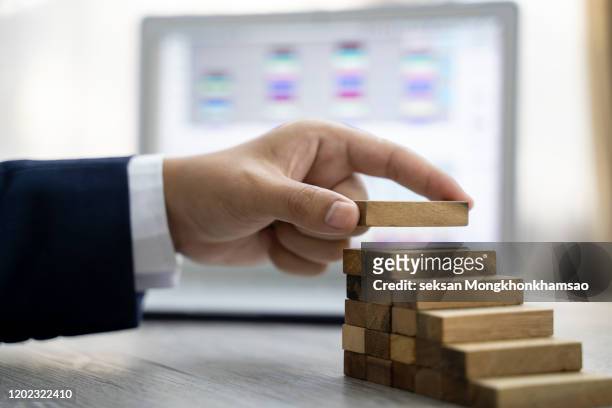 hand arranging wood block stacking as step stair. ladder career path concept for business growth success process - staff benefits corporate stock-fotos und bilder