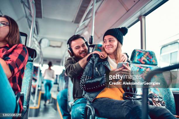 male massaging his female friend while listening to music on a bus trip - massage funny stock pictures, royalty-free photos & images