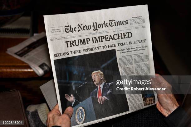 Woman reads the front page of the December 19, 2019 New York Times with its headline reporting the impeachment of U.S. President Donald Trump by the...