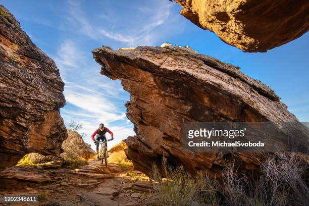 mountain biker riding through boulders in the southwest desert - utah landscape stock pictures, royalty-free photos & images