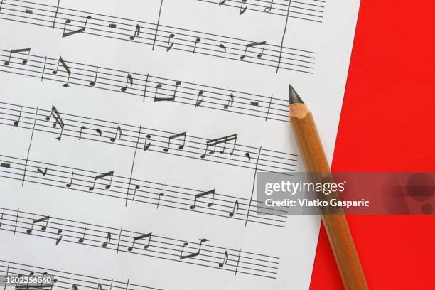 handwritten sheet music on red background - sheet music stock pictures, royalty-free photos & images