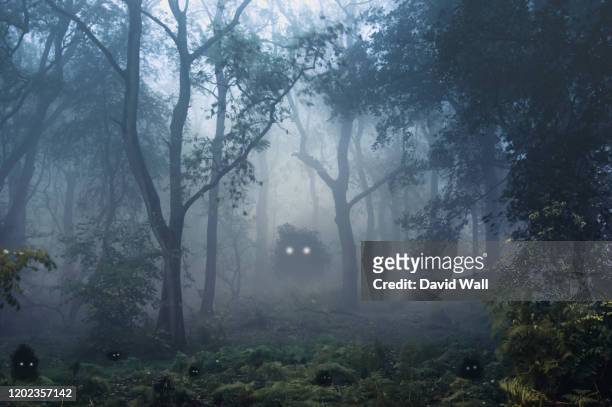 a creepy, fantasy forest of trees, back lighted with spooky, glowing eyes of creatures in the undergrowth. - monstro imagens e fotografias de stock