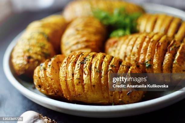 hasselback potatoes. baked accordion potatoes. delicious vegetables. food in a gray clay plate, close-up. - gebackene kartoffel stock-fotos und bilder