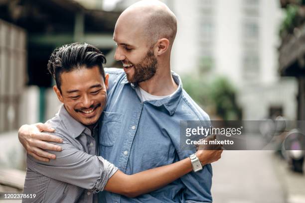 homosexual couple in city - gay man stock pictures, royalty-free photos & images
