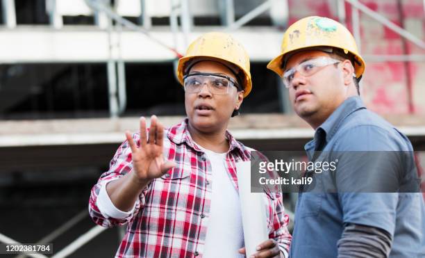 två arbetare som pratar på en byggarbetsplats, tittar - hardhat outside bildbanksfoton och bilder