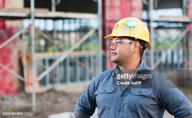 young hispanic man working at a construction site - hispanic construction worker stock pictures, royalty-free photos & images