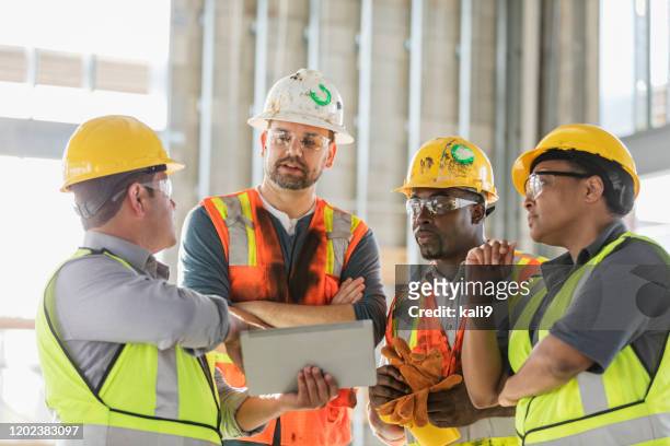trabajadores de la construcción que miran la tableta digital - eye protection fotografías e imágenes de stock