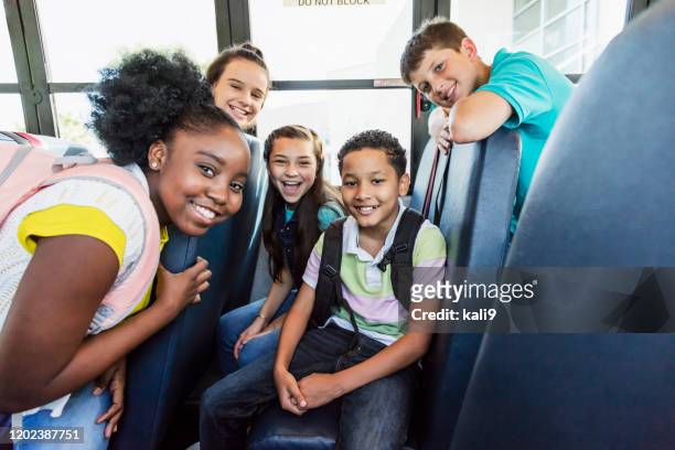 multiethnische junior-high-schüler reiten schulbus - kids sitting together in bus stock-fotos und bilder