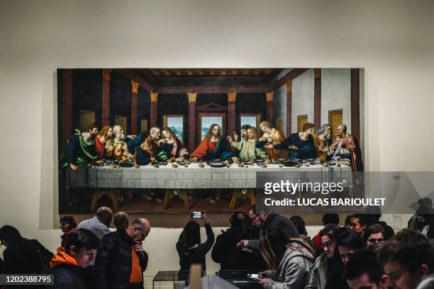 Visitors look at a version of 'The Last Supper' during the night and free opening of the 'Leonardo da Vinci' exhibition at The Louvre Museum on...