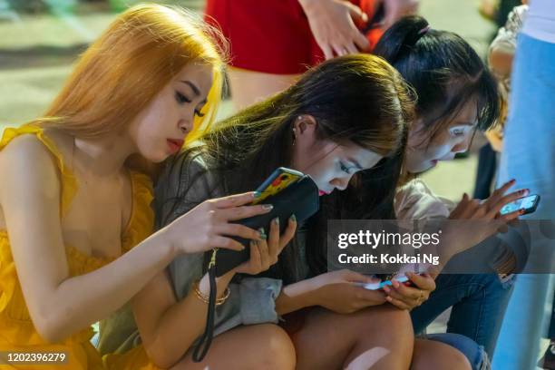 vietnamesische mädchen auf handys während tet festival - vietnam teen stock-fotos und bilder