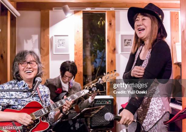 asian senior woman singing in lodge style cafe, talking between performances. - narrar fotografías e imágenes de stock