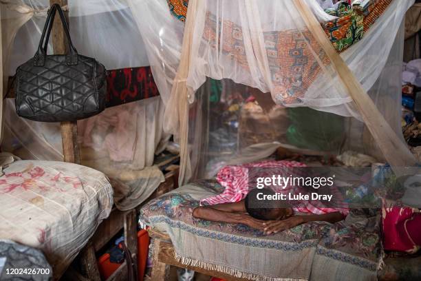 Woman, suffering from malaria, rests on her families bed inside the Povoado slum on January 27, 2020 in Luanda, Angola. Eight families live in this...