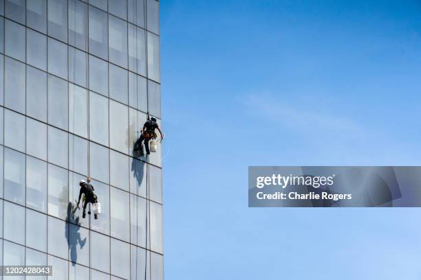 window cleaners cleaning building - window cleaning stock pictures, royalty-free photos & images