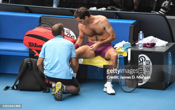 Roger Federer of Switzerland receives medical attention on court during his Men's Singles Quarter Final match against Tennys Sandgren of the United...