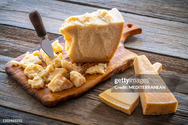 parmesan reggiano cheese on cutting board - parmigiano reggiano stock pictures, royalty-free photos & images