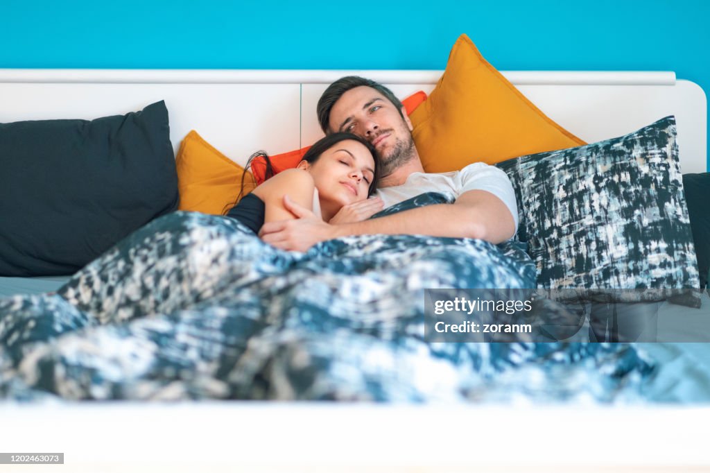 Couple under bed sheets in the early morning