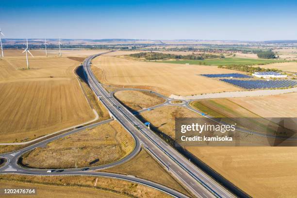 aerial view of wind turbines and solar field on highway - agricultural policy stock pictures, royalty-free photos & images