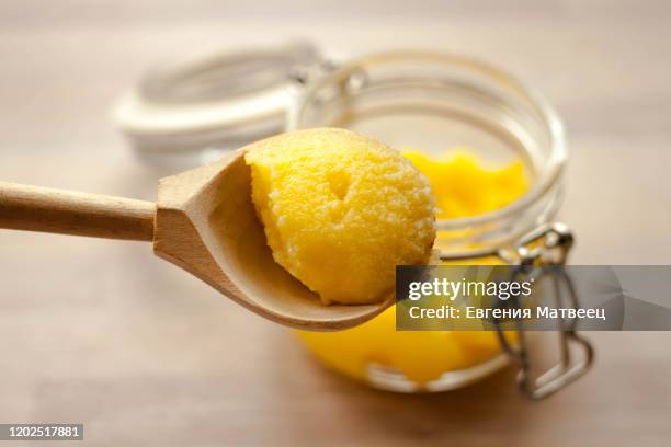 ghee clarified butter desi in glass jar with spoon made from wood on natural wooden background - purity stock pictures, royalty-free photos & images