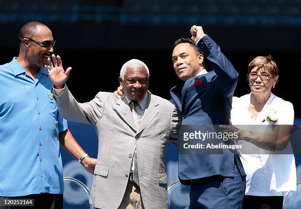 Hall of Famer Roberto Alomar and his father Sandy Alomar wave to the fans with his mother Maria Alomar during a ceremony to retire his during MLB...