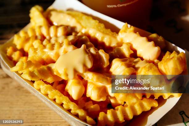 close-up of potato french fries with cheese topping - cheesy fries stock pictures, royalty-free photos & images