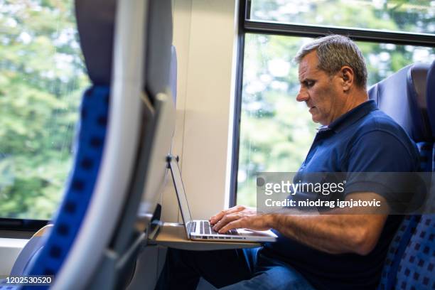 mature man using laptop in high speed train - high speed train germany stock pictures, royalty-free photos & images
