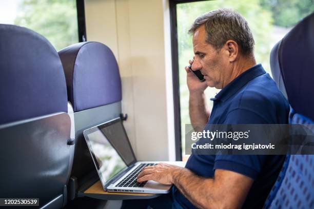 mature man multi-tasking in high speed train - high speed train germany stock pictures, royalty-free photos & images