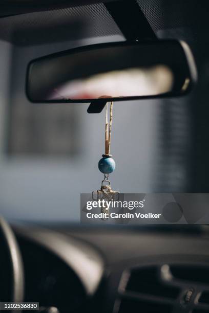 handmade cross hanging from a rear view mirror in a car as a sign of protection and faith. - vehicle mirror stock-fotos und bilder