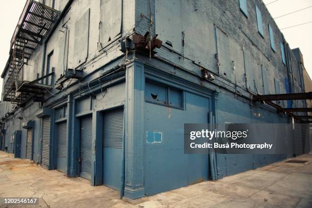 industrial brick building with fire escapes, boarded up windows and metal grates in the meatpacking district, manhattan, new york city - meatpacking district stock pictures, royalty-free photos & images