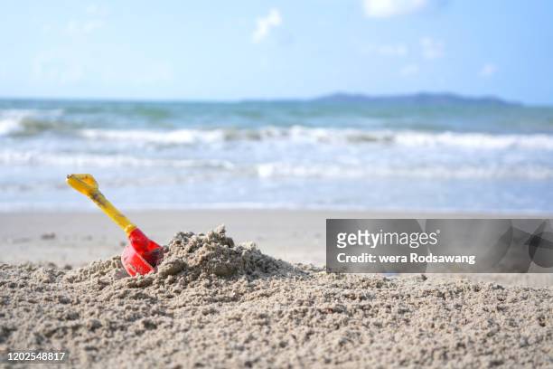 plastic sand shovel placing on the sea beach - bucket and spade stock pictures, royalty-free photos & images
