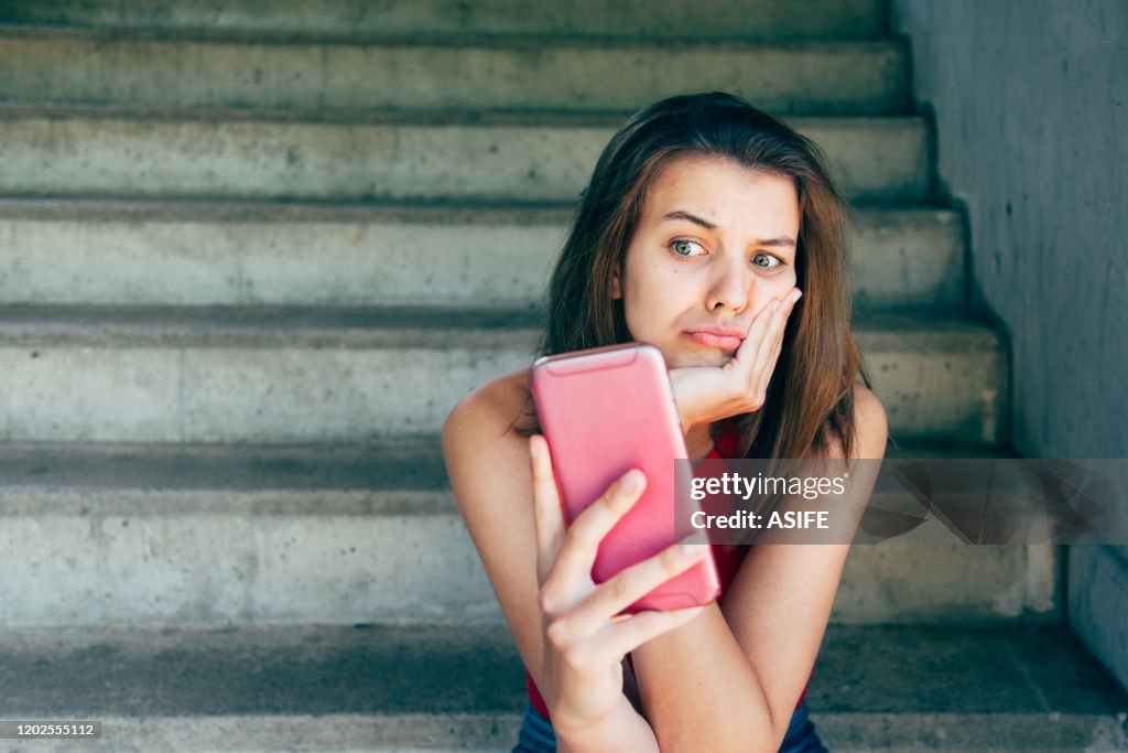 Displeased teen girl looking at her smartphone