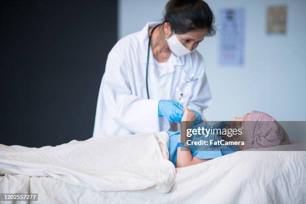 doctor checking on a young cancer patient stock photo - sad child hospital stock pictures, royalty-free photos & images