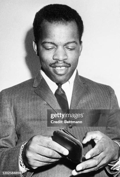 John Lewis, head of the Student Non-Violent Coordinating Committee checks his wallet for his draft card in response to newsmen's questions. Lewis,...