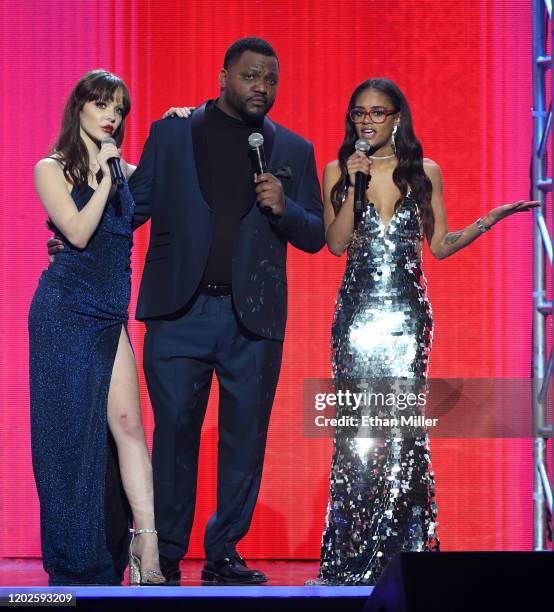 Actor/comedian Aries Spears is flanked by adult film actresses and 2020 AVN Trophy Girls Aliya Brynn and Scarlit scandal during the 2020 Adult Video...