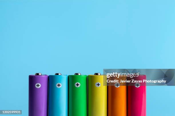 colorful batteries on blue background - alkaline stockfoto's en -beelden