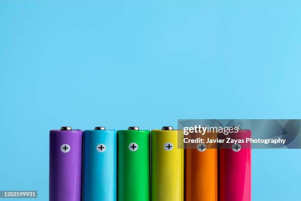 colorful batteries on blue background - alkaline stock pictures, royalty-free photos & images