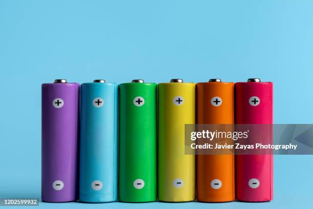 colorful batteries on blue background - social awareness symbol stock-fotos und bilder