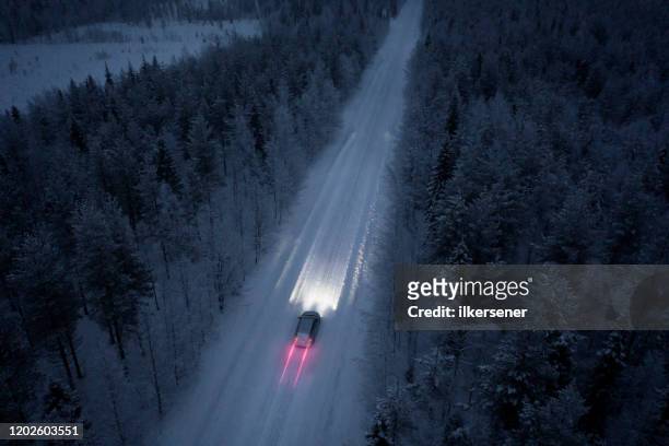 vue aérienne d'une route de neige passant par dans la forêt couverte de neige en finlande - route sapin neige photos et images de collection