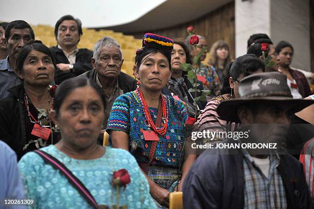 Relatives of victims of the slaugther of the villa Dos Erres hold roses on August 2, 2011 in Guatemala City during the trial of military men...