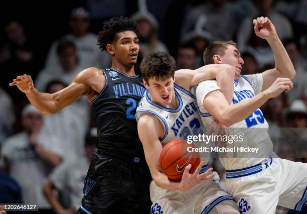 Zach Freemantle and Jason Carter of the Xavier Musketeers get tied up going for the rebound against Jermaine Samuels of the Villanova Wildcats during...